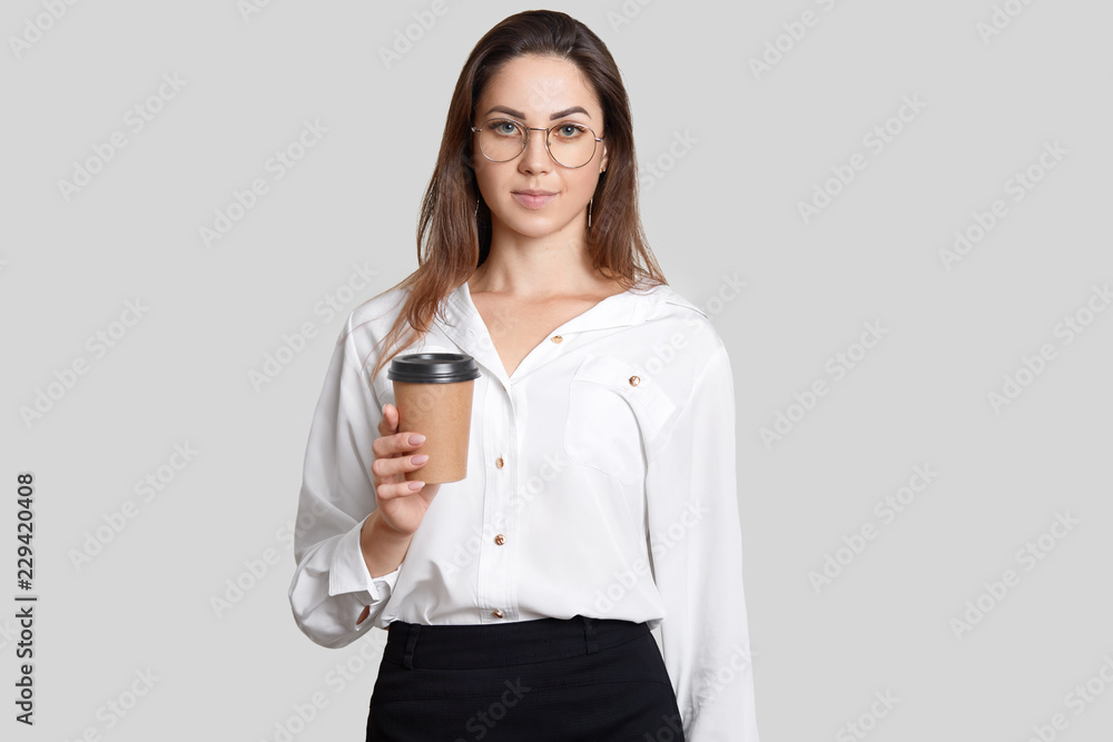 Young student in formal clothes, holds takeaway coffee, wears transparent glasses, holds disposable cup, isolated over white background, has break after classes. Businesswoman with espresso. Young student in formal clothes, holds takeaway coffee, wears transparent glasses, holds disposable cup, isolated over white background, has break after classes. Businesswoman with espresso.