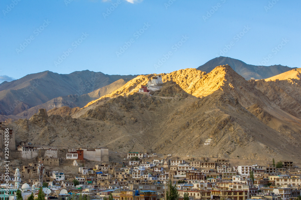 Tibetan temple on a mountain above the city with a flare of the setting sun