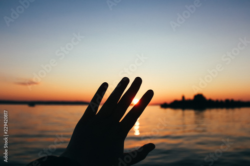 Silhouette of hands on the background of the lake sunset