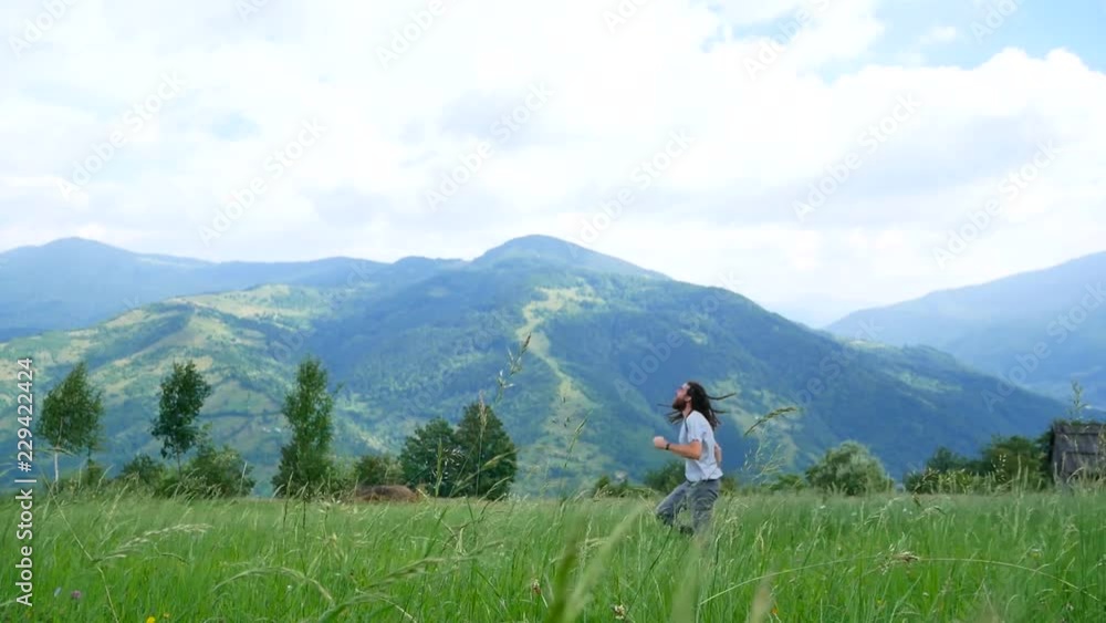 A young man with dreadlocks playing with a model airplane in the mountains A young man with dreadlocks playing with a model airplane in the mountains