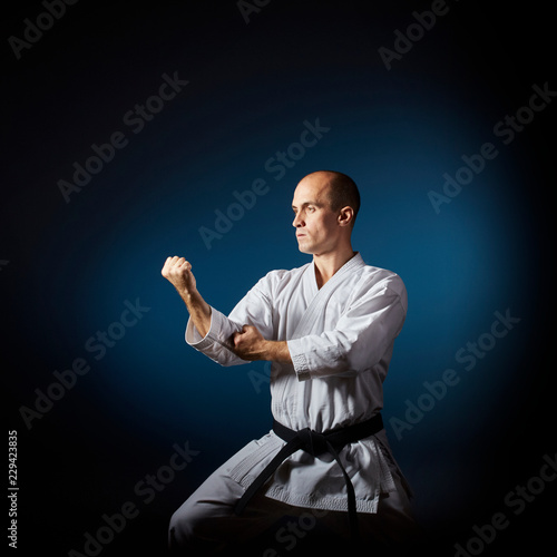 On a blue background with a gradient athlete performs formal karate exercises