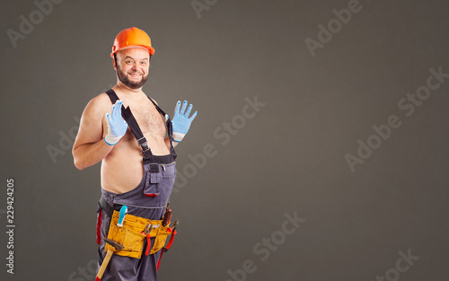 Принти на полотні Funny fat bearded repairman on a gray background.
