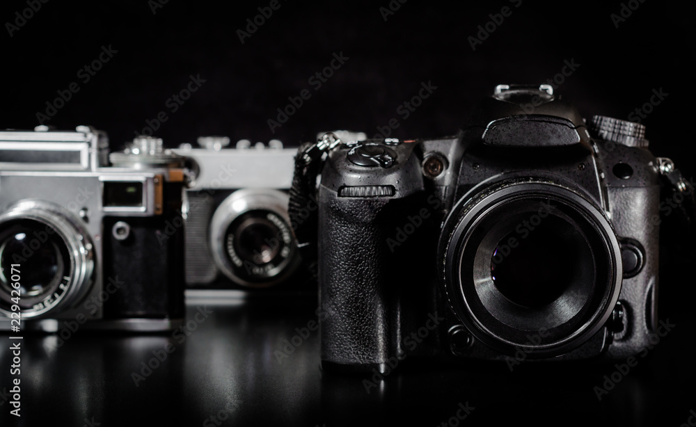 two vintage cameras and one modern camera on a black background closeup