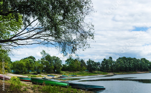 Pier with old fishing boats on the bank of the Pripyat River near the village of Petrikov village. Travel to Belarus. Water landscape photo