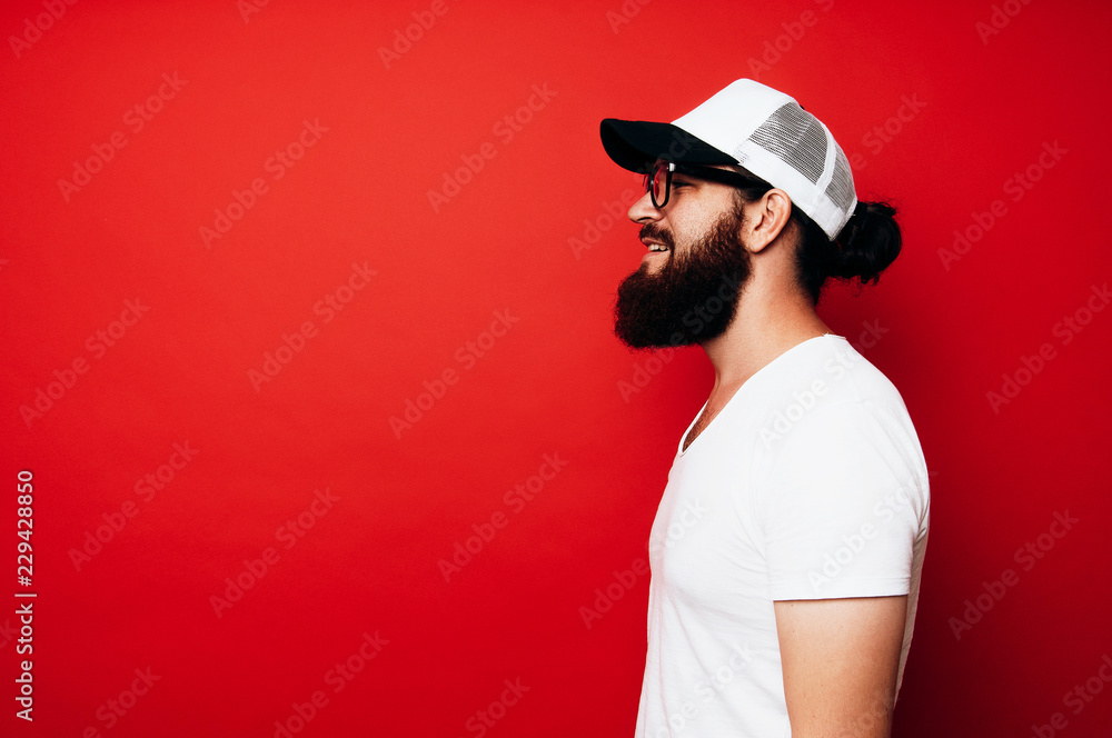Side view of happy bearded man in white t-shirt and wearing white cap
