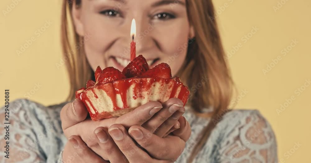 Cheerful beautiful young woman giving birthday cupcake with candle Cheerful beautiful young woman giving birthday cupcake with candle