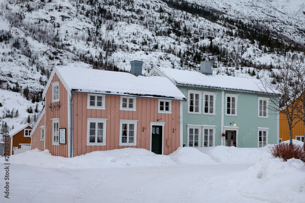 Small wooden houses by the river banks of Vefsna  in Mosjøen city, Northern Norway, House in snow