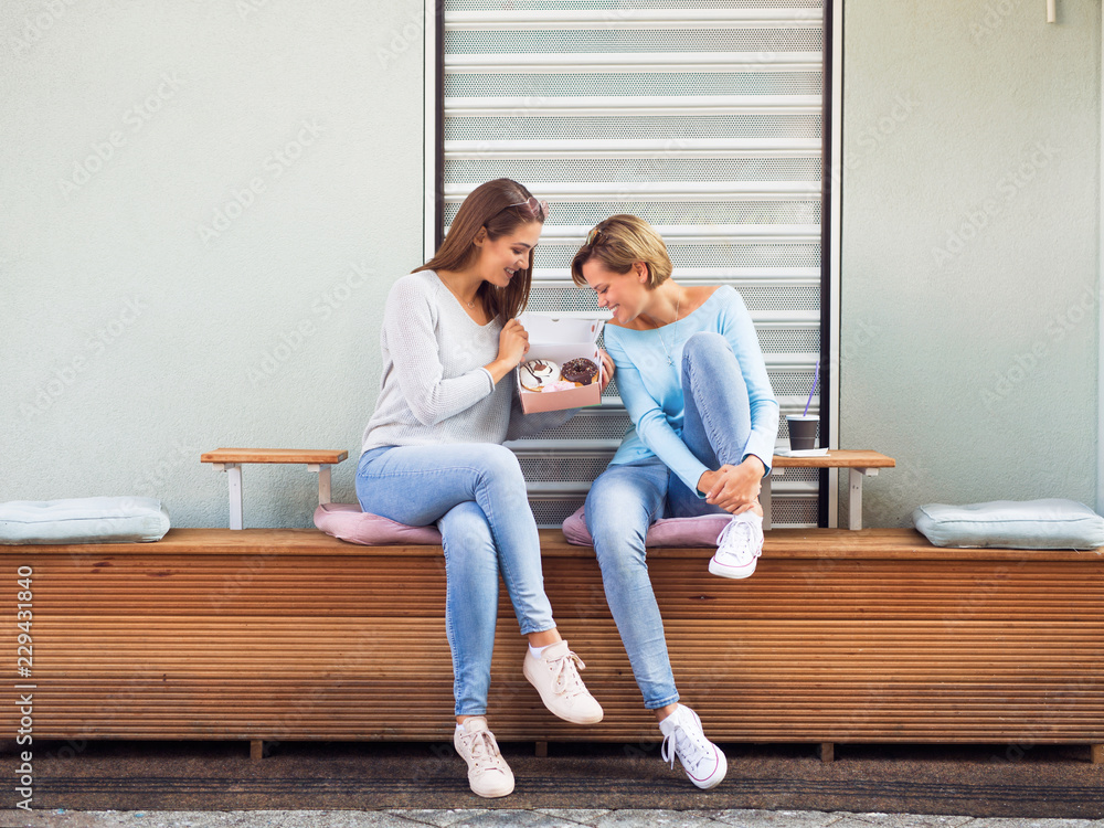 Two young women having fun and eating donuts Two young women having fun and eating donuts