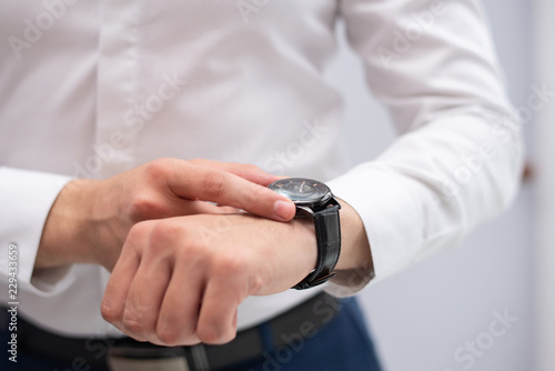 Close-up of businessman looking at his modern wristwatch. Caucasian manager checking time. Time and punctuality concept