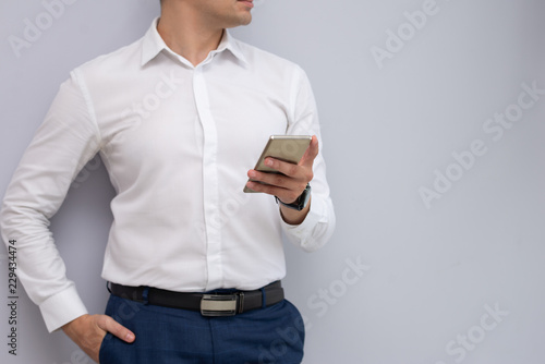 Elegant serious young businessman standing with smartphone. Caucasian manager using smartphone. Businessman concept