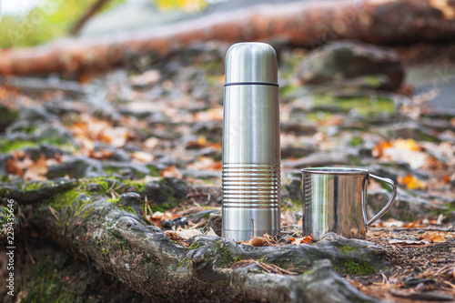 Stainless steel thermos and mug in forest