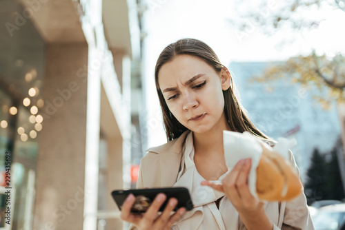 Eating woman with dirty lips working online in a smartphone