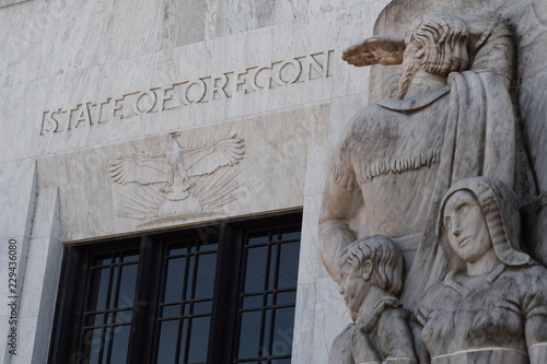 Konstfotografi Text and an eagle carved into marble above the entrance to the Oregon State Capitol building in Salem, part of a marble relief carving representing white settlers in the foreground