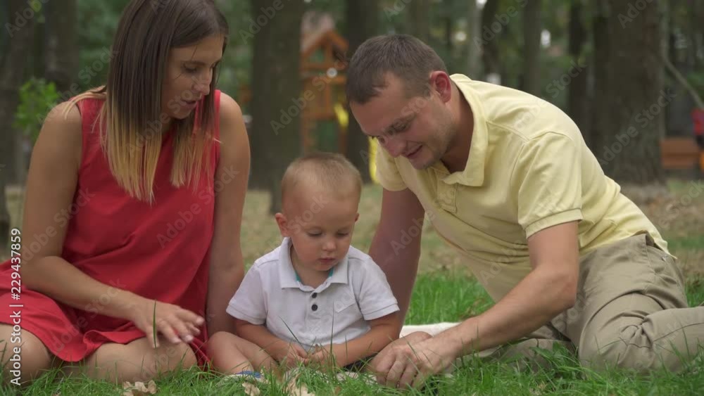 Dad shows his little son an acorn in the park Dad shows his little son an acorn in the park
