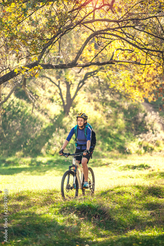 The girl rides a bike in the autumn park.