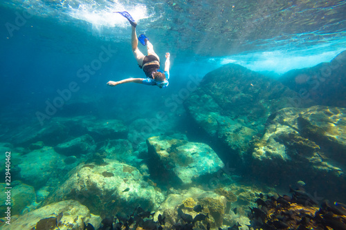Young woman snorkeling in the blue waters of the popular Similan Islands in Thailand, one of the tourist attraction of the Andaman Sea.