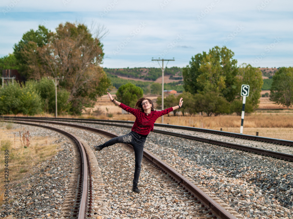 A teenage girl jumping on the train tracks. Concept of freedom and joy