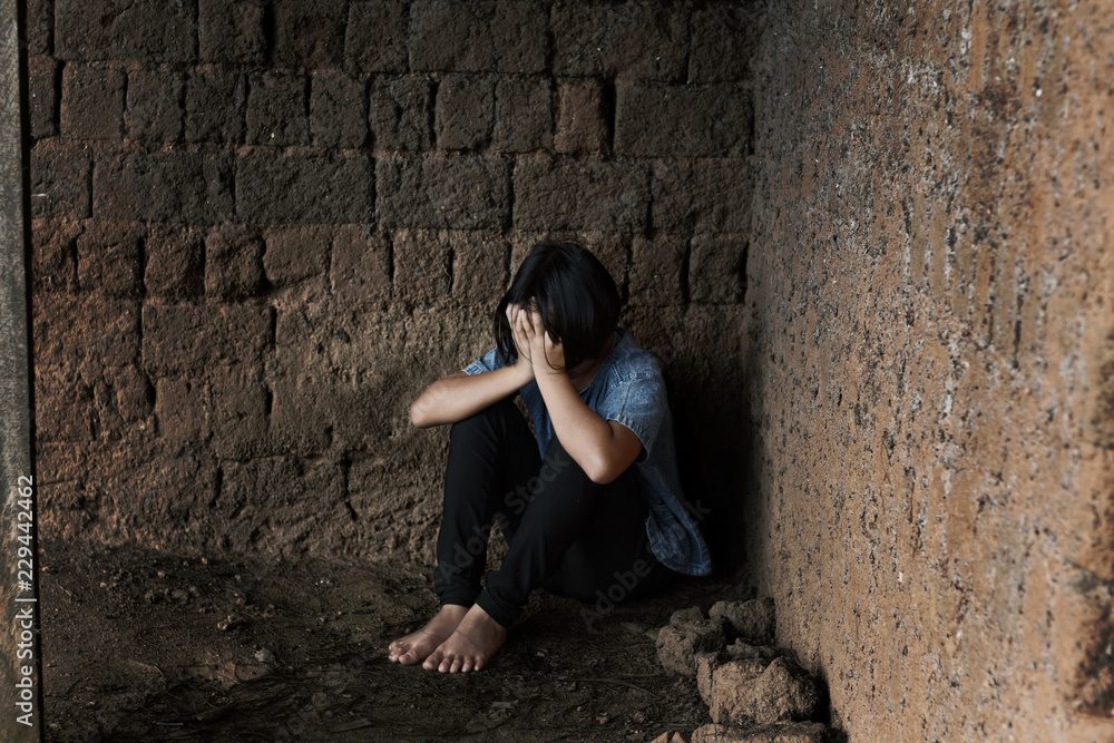 young homeless despair child, little girl sitting on floor against old earth brick wall,children violence and abused concept,human trafficking concept ,Trafficking concept