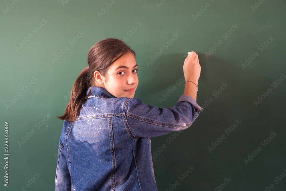 schoolgirl with chalk at the blackboard, school life