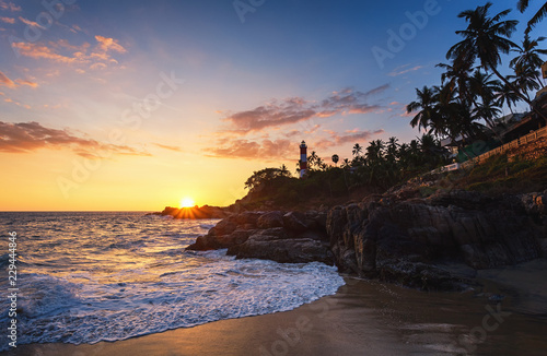 Obraz na płótnie Lighthouse on the hill near the ocean at blue sky with clouds in Kovalam (Vizhinjam beach), Kerala, India. Beautiful sea sunset on the Malabar coast. w salonie