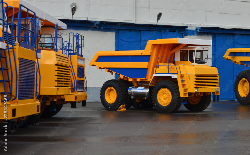 Obraz premium No focus. Huge yellow quarry dump trucks on large wheels at the exhibition of automotive equipment. Zhodino