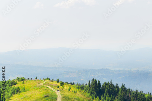 newlyweds hold hands and walk on a dirt road on top of the mountain back to the camera