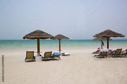 White sand beach, umbrellas, chair and turquoise water of Indean ocean, vacation and relaxing concept.
