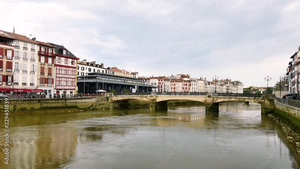 The Marengo bridge is a Bayonne road bridge that crosses the Nive river. Filmed in October 2018. On either side of the shoreline, there are typical old houses. Filmed in a cloudy day. The Marengo bridge is a Bayonne road bridge that crosses the Nive river. Filmed in October 2018. On either side of the shoreline, there are typical old houses. Filmed in a cloudy day.