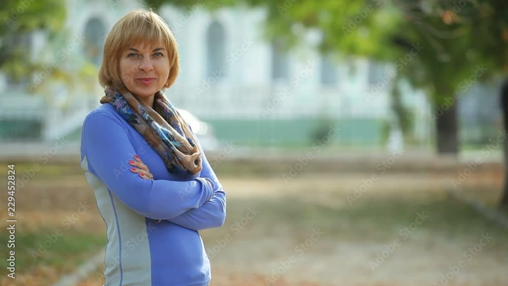 Exciting view of a fashionable blond woman with a bob haircut in a sweatshirt and a scarf standing with crossed arms in semi-profile in autumn Exciting view of a fashionable blond woman with a bob haircut in a sweatshirt and a scarf standing with crossed arms in semi-profile in autumn