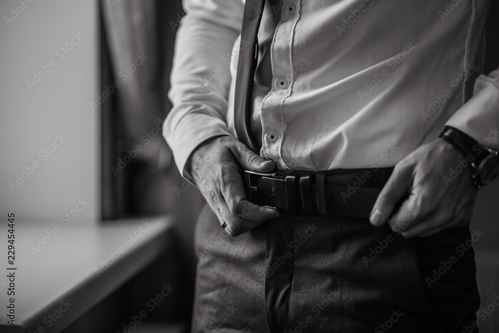 Groom in black tuxedo and bowtie correct his buttons on white shirt. Wedding. Details Groom in black tuxedo and bowtie correct his buttons on white shirt. Wedding. Details