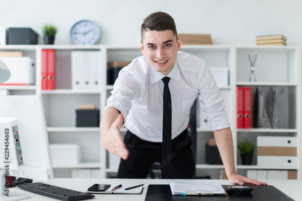 Fototapeta premium The young man in the office stands up and stretches his hand forward.