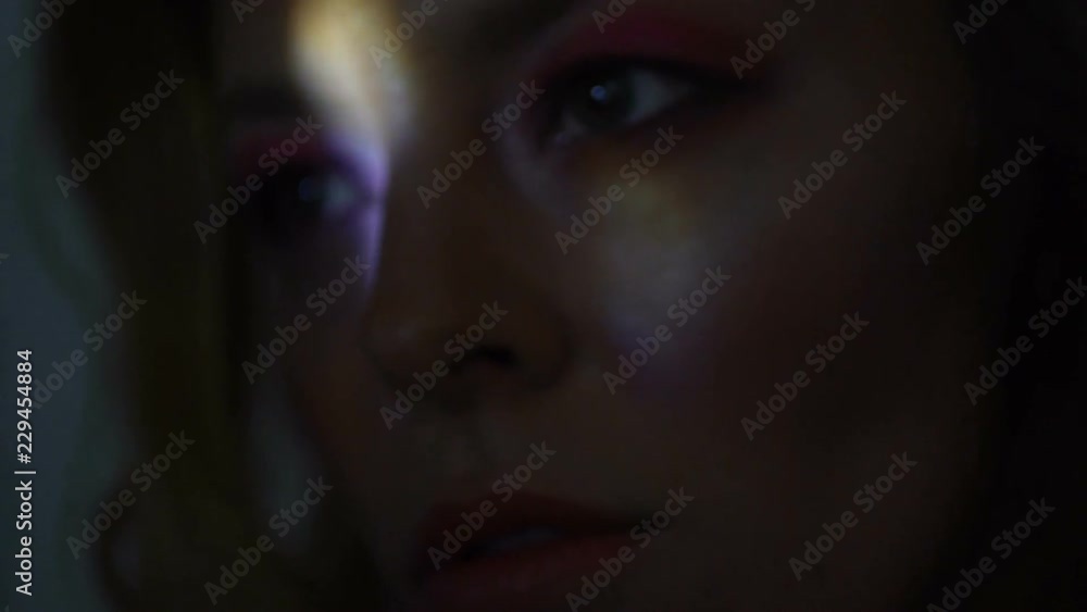 Colored light beams illuminating face of young woman, darkness loneliness Colored light beams illuminating face of young woman, darkness loneliness