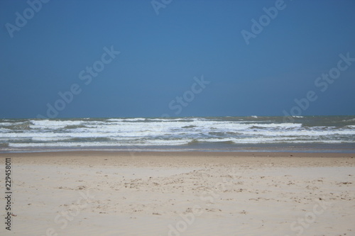 Beautiful beach with clear blue sky and white sand with some waves coming from the ocean