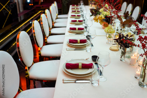 perspective decorated table in a restaurant with plates and napkins and wine glasses decorated with flowers