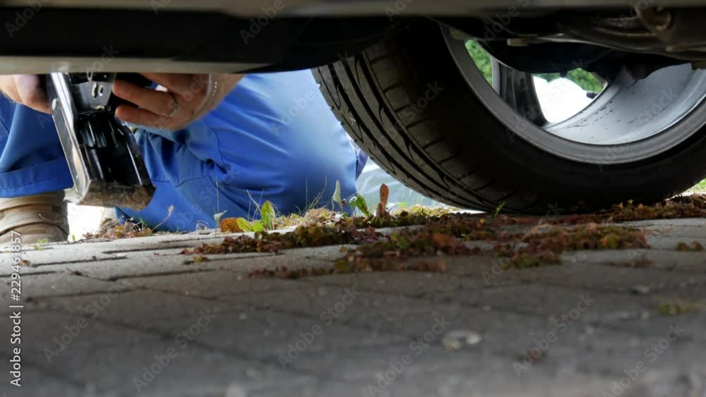 A man in work trousers replaces a car wheel A man in work trousers replaces a car wheel