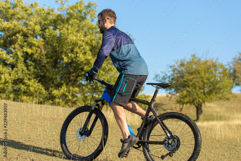 Cyclist in shorts and jersey on a modern carbon hardtail bike with an air suspension fork