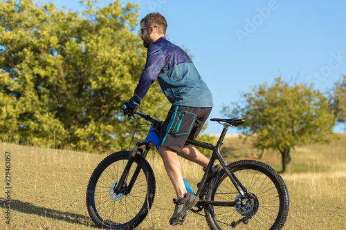 Cyclist in shorts and jersey on a modern carbon hardtail bike with an air suspension fork