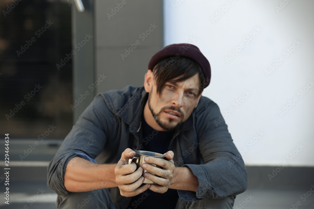 Poor man with mug begging on city street Poor man with mug begging on city street