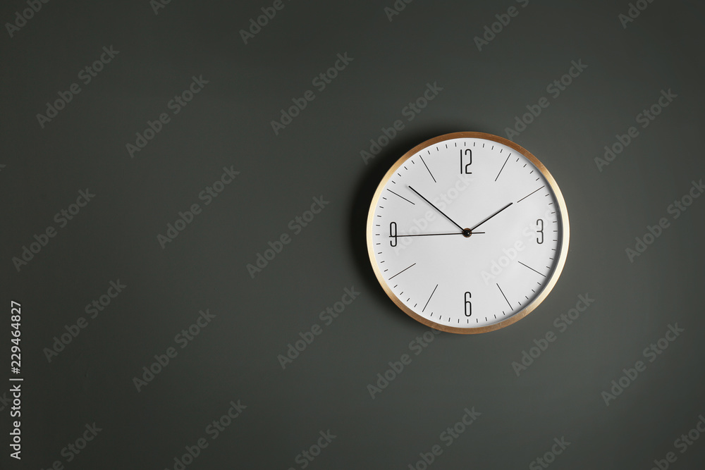Stylish analog clock hanging on gray wall, space for text. Time of day Stylish analog clock hanging on gray wall, space for text. Time of day