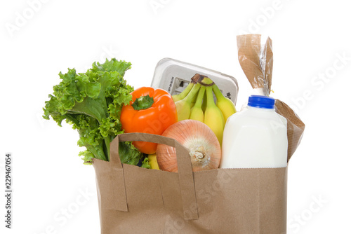 Brown eco friendly grocery bag with bottle of milk, carton of eggs, bag of bread, bananas, lettuce, bell pepper and onion, isolated on white. Healthy shopping.