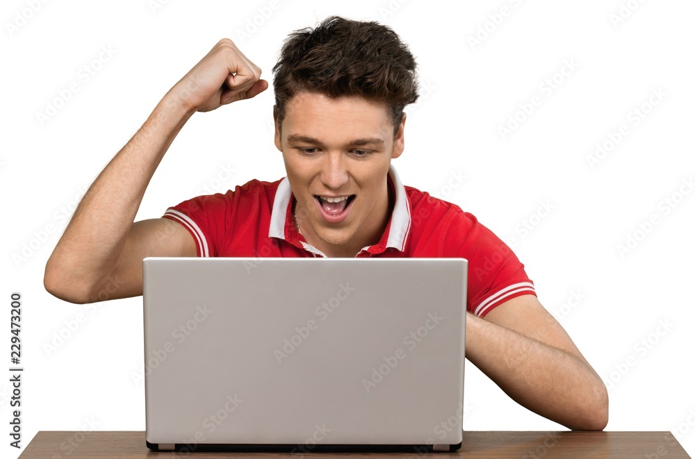 Young man cheering at his computer Young man cheering at his computer