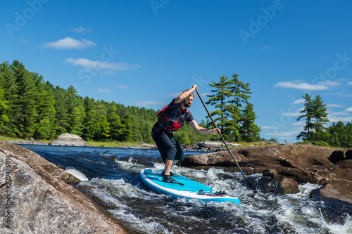 Man paddling whitewater on a a stand up paddle board
