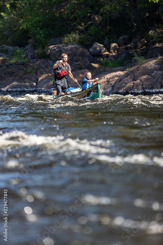 Fototapeta Naklejka Na Ścianę i Meble -  Father and daughter paddle a canoe on whitewater in the Canadian wilderness