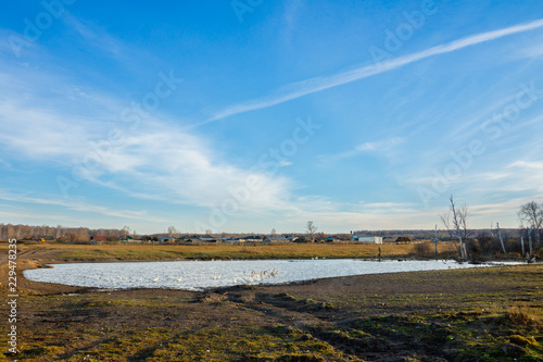 Autumn field with old dry grass and dirty roads