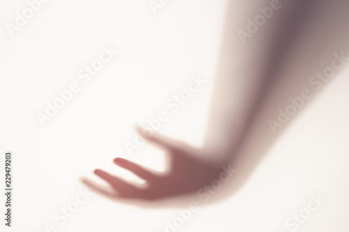 The concept of the shadow of hand behind frosted glass illuminated from behind.