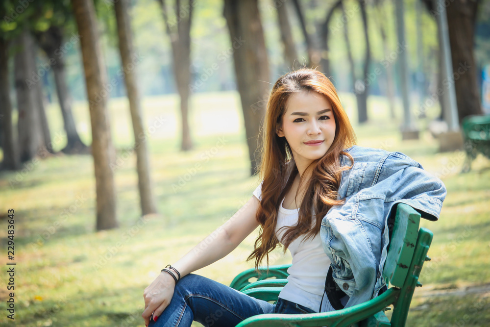 Portrait Asian woman wearing a T-shirt and jeans. Are happy in the public park Portrait Asian woman wearing a T-shirt and jeans. Are happy in the public park