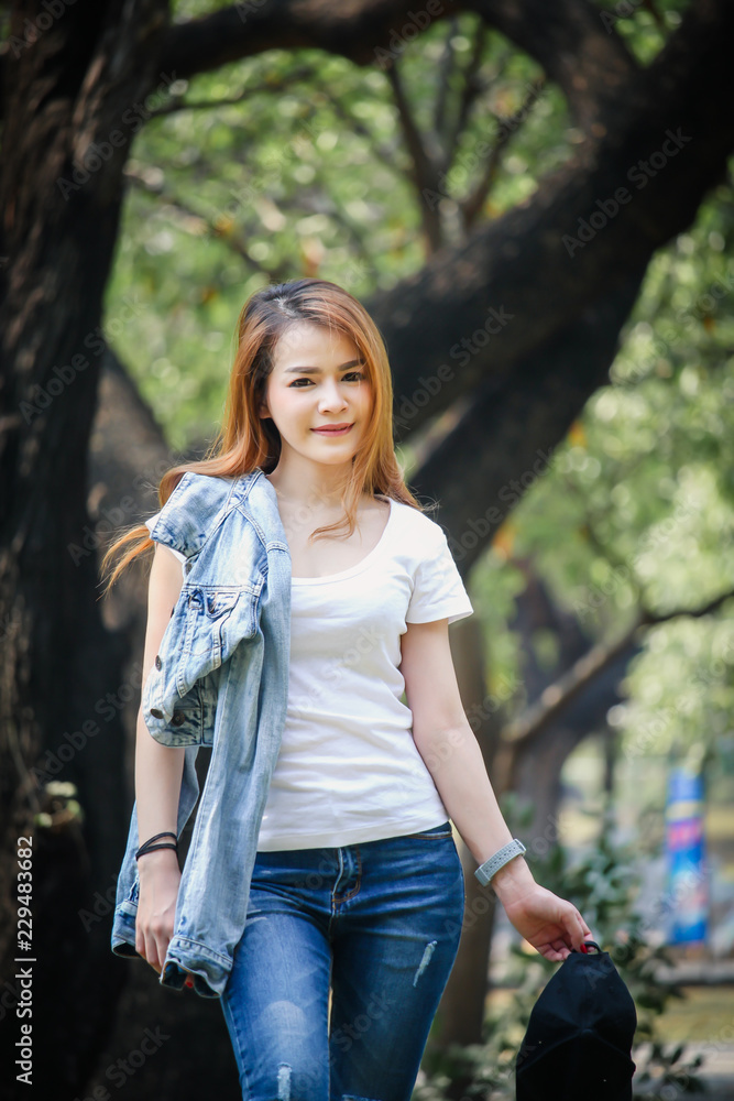 Portrait Asian woman wearing a T-shirt and jeans. Are happy in the public park Portrait Asian woman wearing a T-shirt and jeans. Are happy in the public park