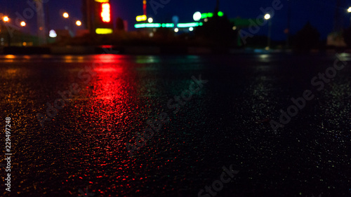 Background of wet asphalt with neon light. Blurred background, night lights of a big city, reflection, puddles. Dark neon bokeh. photo