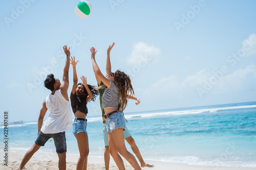 Group of cheerful young people playing with volley ball