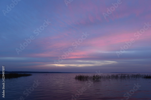 Blue sky in twilight glow above the water of the lake on a warm autumn evening